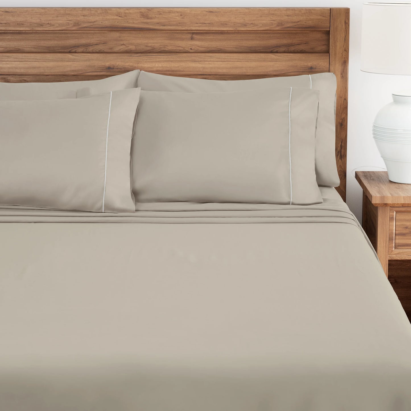 Pumice Stone bed sheets and pillows on a wooden bed with a wooden headboard.