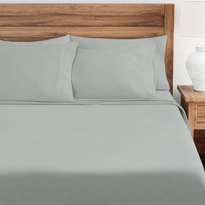 Oystershell bed sheets and pillows on a wooden bed with a white nightstand.
